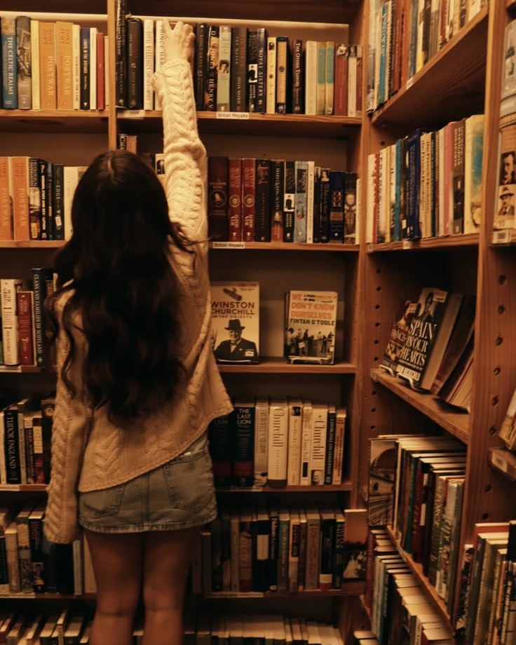 A young reader reaching up to a high shelf in a bookshop
