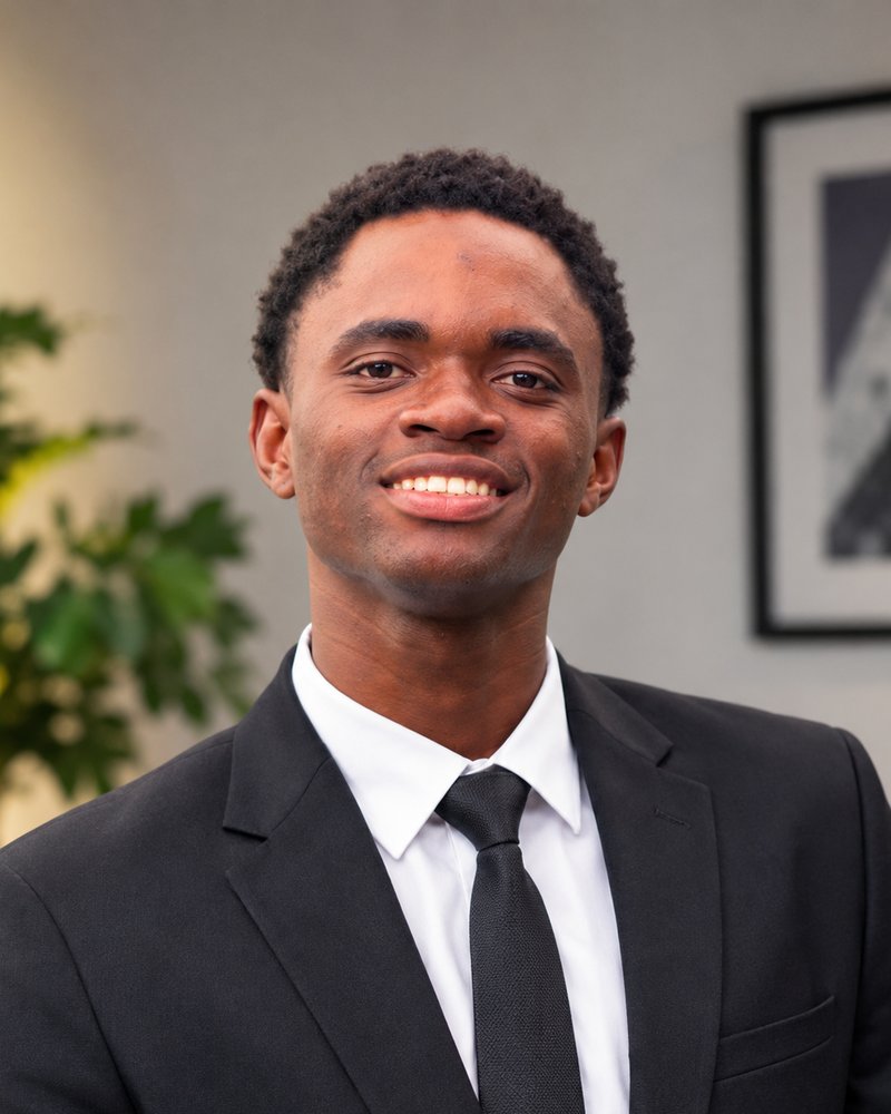 Portrait of Abubakar Sadiq Muhammed, founder of Optivora Ink, smiling in a dark suit and white shirt